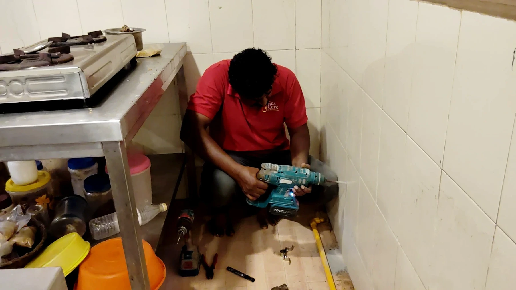 Image of a gas care professional drilling the wall to install an LPG pipe line in a workplace commercial kitchen