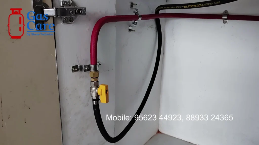 image of a copper pipe line beneath the kitchen cabinet, which is subsequently connected to the cooktop via high-quality rubber tubing. Gas care logo and gas care contact numbers are visible.