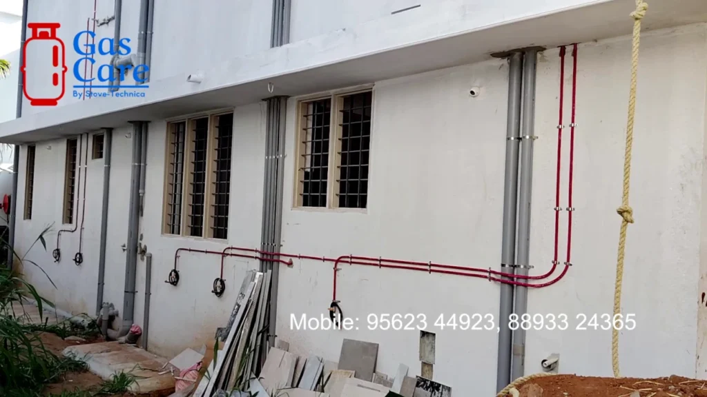 Image of gas care's gas copper pipe line work in an apartment complex, with multiple gas lines running from the ground floor to various flats on the upper floor via the wall. gas care logo and contact number is also visible on the image.